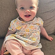 Leighton is registered to the contest to win money with this photo: baby, child, clothing, couch, cute, face, floral_pattern, flower, happy, headband, indoors, infant, pastel_colors, person, pink_pants, portrait, sitting, smiling, soft_lighting, texture
