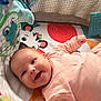 baby, infant, smiling, crib, playmat, toy, colorful, pink_clothing, happy, child, indoor, face, cute, young, person, baby_toys, soft_lighting, fabric, patterned, playtime