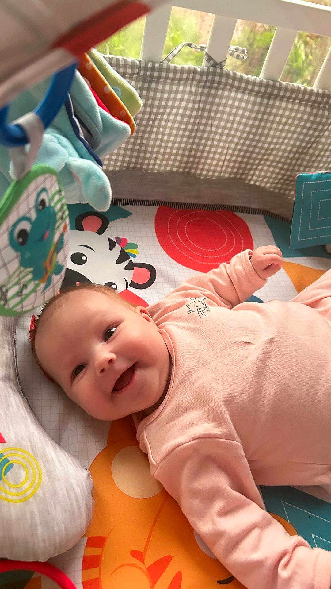 Elena a rejoint le concours — aidez-le/la à gagner de superbes lots ! baby, infant, smiling, crib, playmat, toy, colorful, pink_clothing, happy, child, indoor, face, cute, young, person, baby_toys, soft_lighting, fabric, patterned, playtime