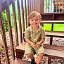 black_socks, casual_clothing, child, cute, daylight, greenery, happy, nature, outdoor, person, portrait, railing, relaxed, sitting, small_child, smiling, toddler, wood, wooden_stairs, young_child