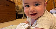 Elijah is registered to the contest to win money with this photo: baby, infant, smile, happy, cute, blanket, quilt, cloth, indoor, carpet, lamp, wood_paneling, furniture, person, portrait, face, child, crawling, cozy, warm_lighting