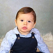 Leeroy a rejoint le concours — aidez-le/la à gagner de superbes lots ! baby, child, portrait, face, curly_hair, blue_shirt, overalls, cute, indoor, soft_background, fluffy_surface, young, infant, sitting, eyes, expression, buttoned_clothing, head, person, photography