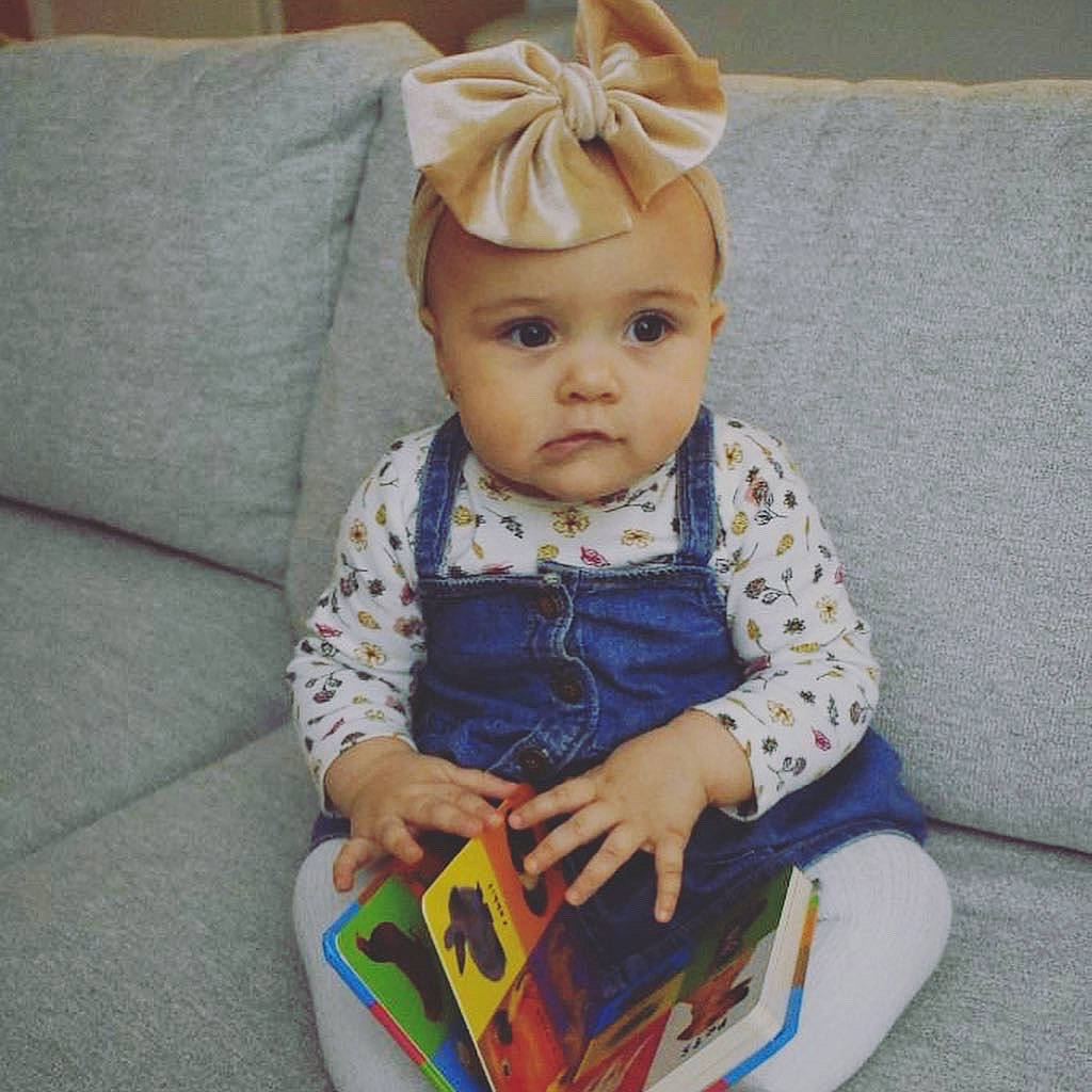 Analiyah is registered to the contest to win money with this photo: baby, baby_products, baby_toddler_clothing, baby_toys, cheek, child, costume_hat, couch, dress, fashion_accessory, head, headband, pattern, person, product, sitting, skin, sleeve, sock, toddler