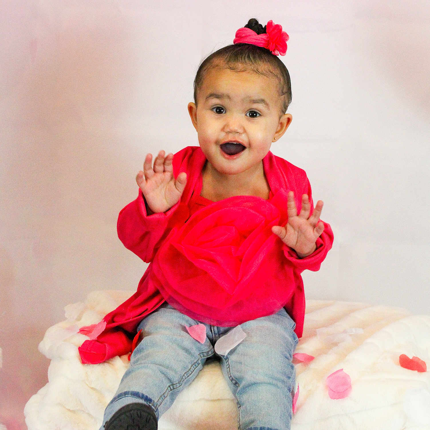 Kaioni joined the competition — help win amazing prizes! baby, blanket, child, cute, face, flower_hair_accessory, footwear, hands, happy, indoors, jeans, pink_petals, playful, portrait, red_clothing, sitting, smiling, studio_photo, toddler, young_child