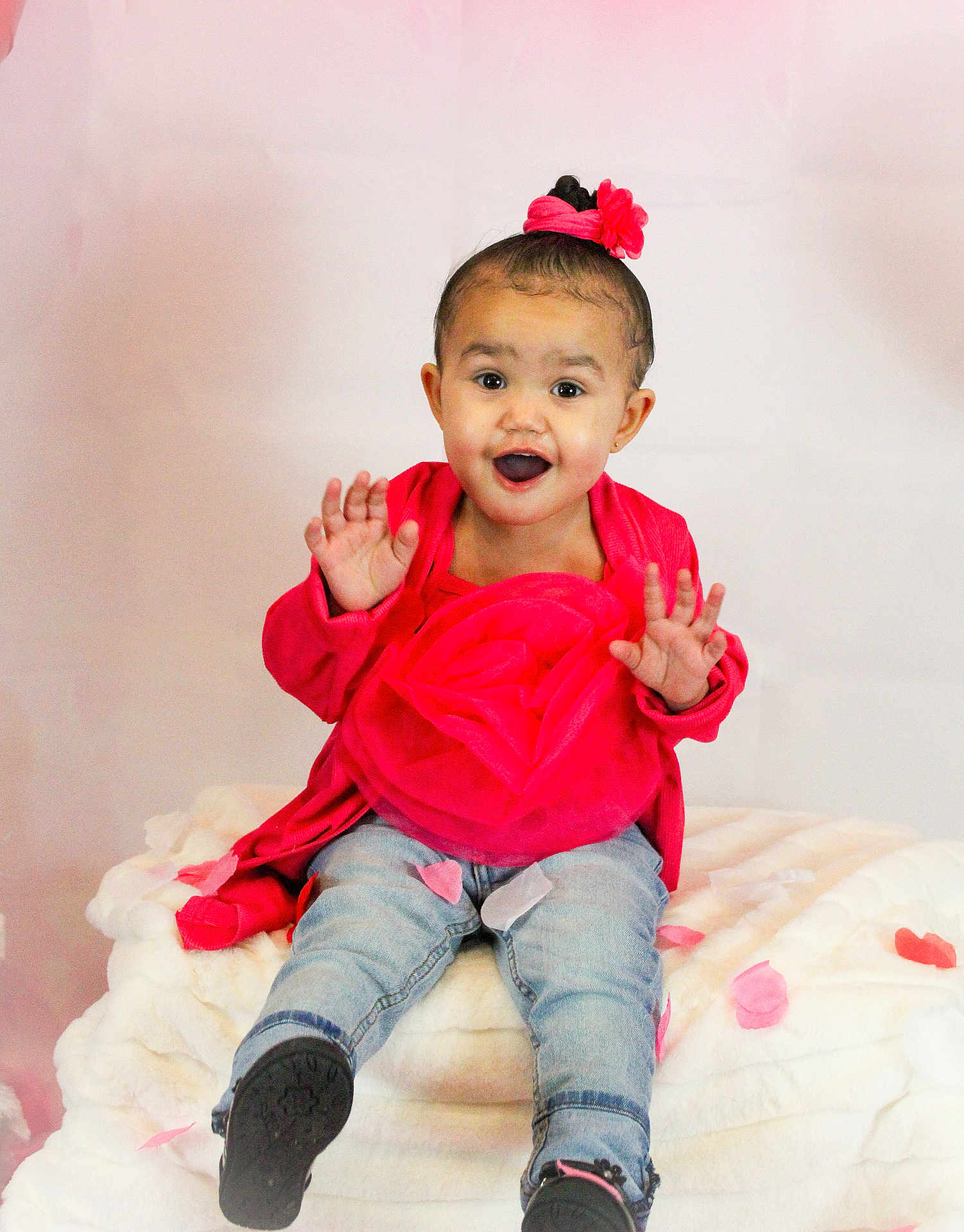 Kaioni joined the competition — help win amazing prizes! baby, blanket, child, cute, face, flower_hair_accessory, footwear, hands, happy, indoors, jeans, pink_petals, playful, portrait, red_clothing, sitting, smiling, studio_photo, toddler, young_child