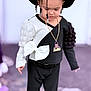 accessories, beads, black_hat, black_pants, bow, braids, casual, child, clothing, cute, expression, fashion, long_sleeve, necklace, outdoor, portrait, standing, style, toddler, young_child