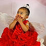 Kaioni joined the competition — help win amazing prizes! angel_wings, baby, background, child, curly_hair, cute, dress, hair_accessory, hands_on_face, indoor, innocent, person, portrait, red_dress, sitting, smile, studio, toddler, white_feathers, young_child