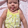 Sophia is registered to the contest to win money with this photo: baby, infant, child, portrait, smiling, tongue_out, lying_down, pink_blanket, yellow_outfit, floral_pattern, dark_hair, face, eyes, cheeks, indoor, cozy, cute, close_up, sitting, photography