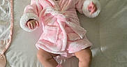 Sophia is registered to the contest to win money with this photo: baby, infant, child, portrait, pink_robe, hood, blanket, changing_mat, bed, lying_down, face, eyes, hair, hands, legs, socks, shoes, indoor, home, textile