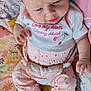 baby, infant, child, pink_clothing, patterned_pants, white_shirt, cherry_design, blanket, colorful, cute, indoors, sitting, footwear_free, curious_expression, soft_light, small_hands, head, face, young_child, cozy