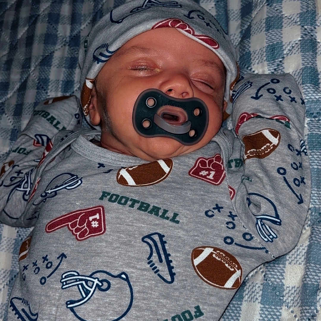 Kingston joined the competition — help win amazing prizes! baby, sleeping, pacifier, hat, football_theme, onesie, infant, blanket, patterned_clothing, cozy, resting, cute, child, soft_lighting, indoor, portrait, newborn, face, peaceful, hands_up