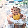 Heavenly is registered to the contest to win money with this photo: baby, child, smiling, outdoor, sunlight, baby_walker, hat, yellow_clothing, pool, grass, sand, playground, happy, person, seat, summer, garden_hose, toys, headwear, infant