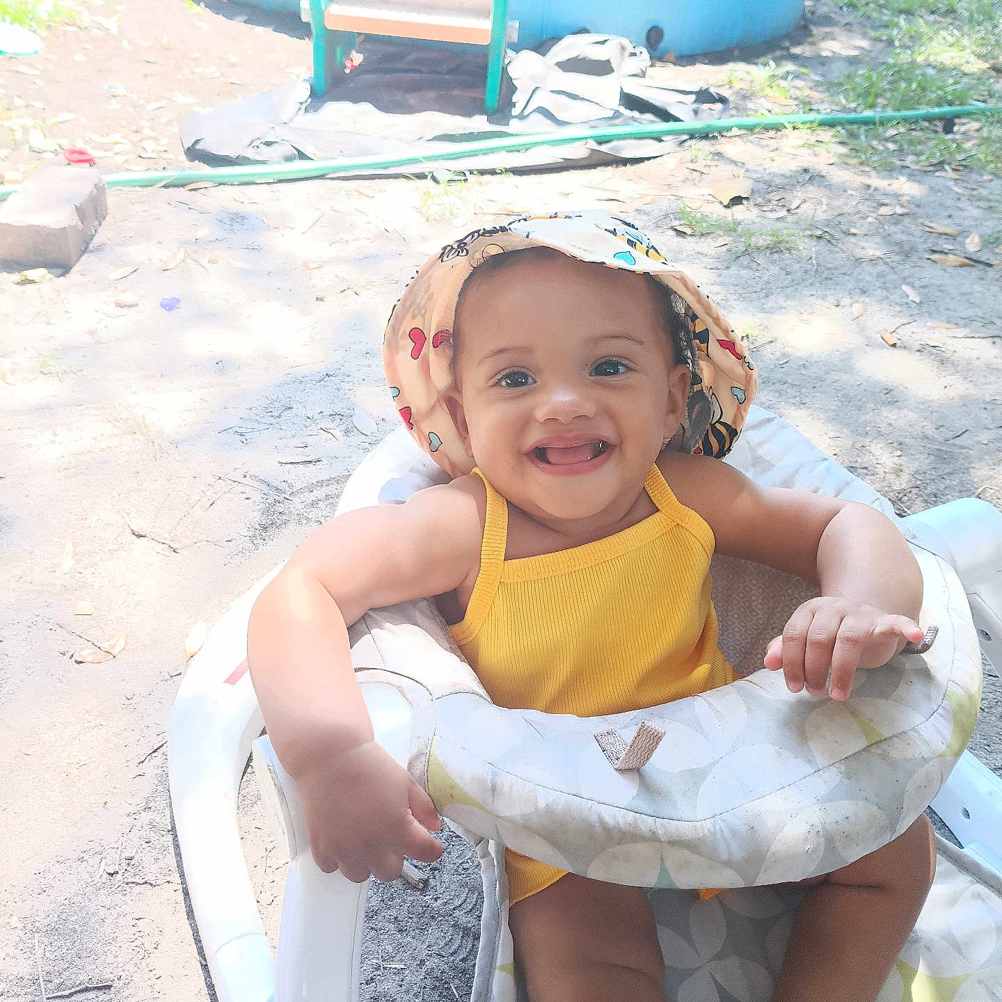 Heavenly is registered to the contest to win money with this photo: baby, child, smiling, hat, yellow_outfit, baby_walker, outdoor, sunlight, grass, pool, playground, happy, infant, summer, seat, person, cute, nature, fun, toddler