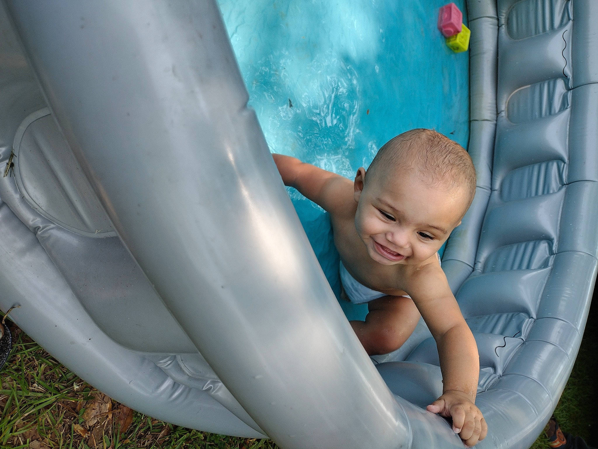 Delonta is registered to the contest to win money with this photo: arm, auto_part, automotive_design, automotive_exterior, automotive_tire, baby, child, chute, fun, grass, happy, joy, leisure, person, plant, plastic, plumbing, recreation, sitting, smile
