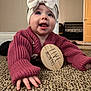 baby, infant, headband, bow, sweater, pink, carpet, floor, hand, milestone, wooden_sign, indoor, cute, smiling, person, child, young, portrait, crawling, home