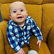 Atlas is registered to the contest to win money with this photo: baby, child, infant, blue_checkered_shirt, mustard_pants, white_booties, smiling, sitting, indoor, cozy_chair, textured_chair, happy, cute, portrait, young_child, looking_up, small_hands, comfortable, casual_clothing, plush_chair