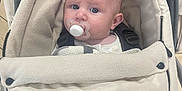 Ronnie-Lee is registered to the contest to win money with this photo: baby, pacifier, stroller, infant, blanket, clothing, face, head, blue_eyes, expression, seated, comfort, warm, indoor, child, person, cute, closeup, portrait, neutral_colors