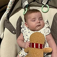 Bonnie joined the competition — help win amazing prizes! baby, sleeping, plush_toy, gingerbread_man, infant, baby_seat, soft_toys, cozy, child, cute, peaceful, white_dress, patterned_clothes, indoor, resting, toddler, face, hand, comfort, nap