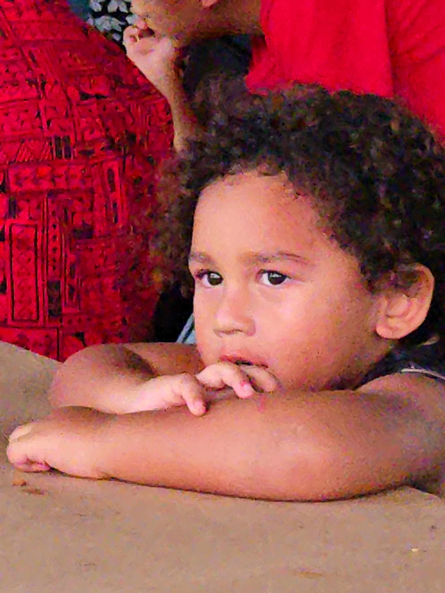 Isaac Mokihana joined the competition — help win amazing prizes! arms, casual, child, closeup, contemplative, curly_hair, expression, face, indoor, natural_light, patterned_fabric, person, portrait, red_fabric, relaxed, resting, skin, table_surface, thoughtful, young