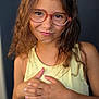 Yliènna a rejoint le concours — aidez-le/la à gagner de superbes lots ! child, girl, glasses, yellow_tank_top, pineapple_print, curly_hair, smile, face, portrait, hands, playful, standing, casual_clothing, indoors, young, cute, person, skin, expression, fashion
