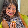 Yliènna participe au concours pour gagner de l'argent avec cette photo : child, girl, smiling, food, holding, curly_hair, brown_hair, dressed, floral_pattern, cushion, green, polka_dots, happy, portrait, closeup, indoors, face, person, casual, seated