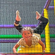Yliènna participe au concours pour gagner de l'argent avec cette photo : child, playground, indoor, net, colorful, play, upside_down, smiling, fun, activity, person, casual_clothing, hair, yellow, purple, green, red, black_pants, happy, leisure