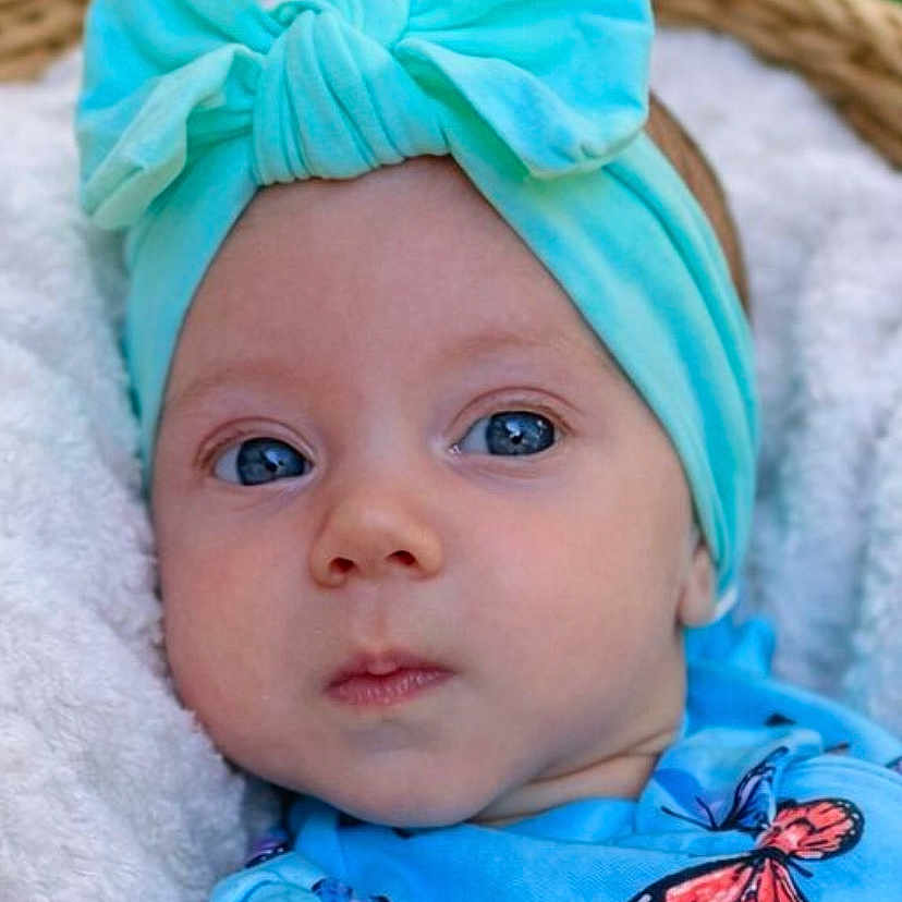 Melani is registered to the contest to win money with this photo: baby, baby_girl, blanket, blue_clothing, bow, butterfly_pattern, child, closeup, colorful, cute, eyes, face, headband, headwear, infant, natural_light, outdoor, portrait, soft_texture, young_child