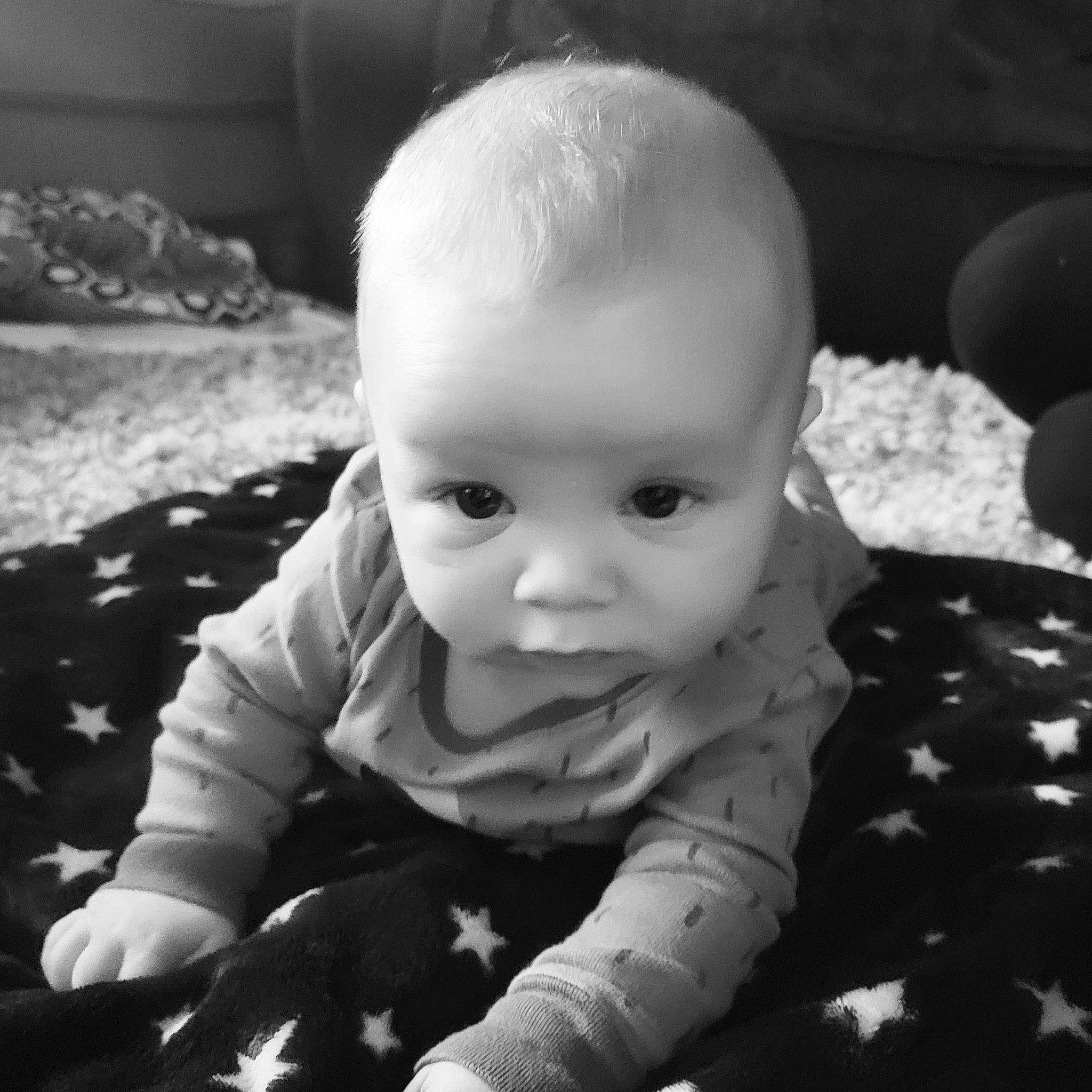 Titus is registered to the contest to win money with this photo: baby, baby_toddler_clothing, beauty, black, black_and_white, cheek, child, comfort, eye, flash_photography, grass, happy, head, iris, monochrome, monochrome_photography, person, skin, standing, toddler