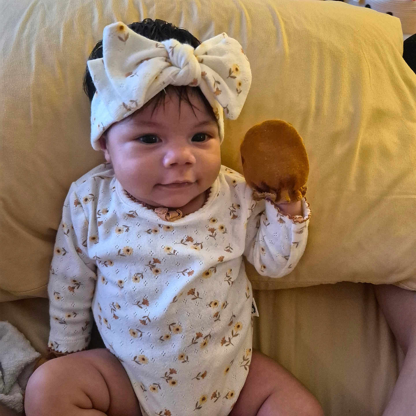 Ila Eternity joined the competition — help win amazing prizes! baby, child, infant, bow, headband, onesie, floral_clothing, toy, plush_toy, sitting, couch, cushion, indoor, home, portrait, smiling, face, dark_hair, cozy, photography