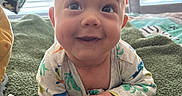 Rownin joined the competition — help win amazing prizes! baby, smiling, infant, blanket, green_blanket, dinosaur_onesie, toy, window_blinds, indoor, happy, cute, face, child, toddler, lying_down, soft_texture, playful, bright, close_up, portrait