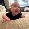 baby, infant, smiling, black_shirt, pillow, indoor, window, blinds, hand, face, happy, child, person, bedroom, soft_texture, home, furniture, light, cute, expression