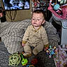 baby, child, infant, sleepy, sitting, striped_pajamas, onesie, blanket, bed, nursery, playroom, toys, rattle, stuffed_animal, television, indoors, portrait, face, dark_hair, date_stamp