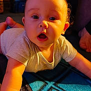 Takoda is registered to the contest to win money with this photo: baby, child, infant, crawling, portrait, face, eyes, open_mouth, curious, surprised, smiling, short_hair, t_shirt, indoor, home, blanket, warm_lighting, sunlight, furniture, photography