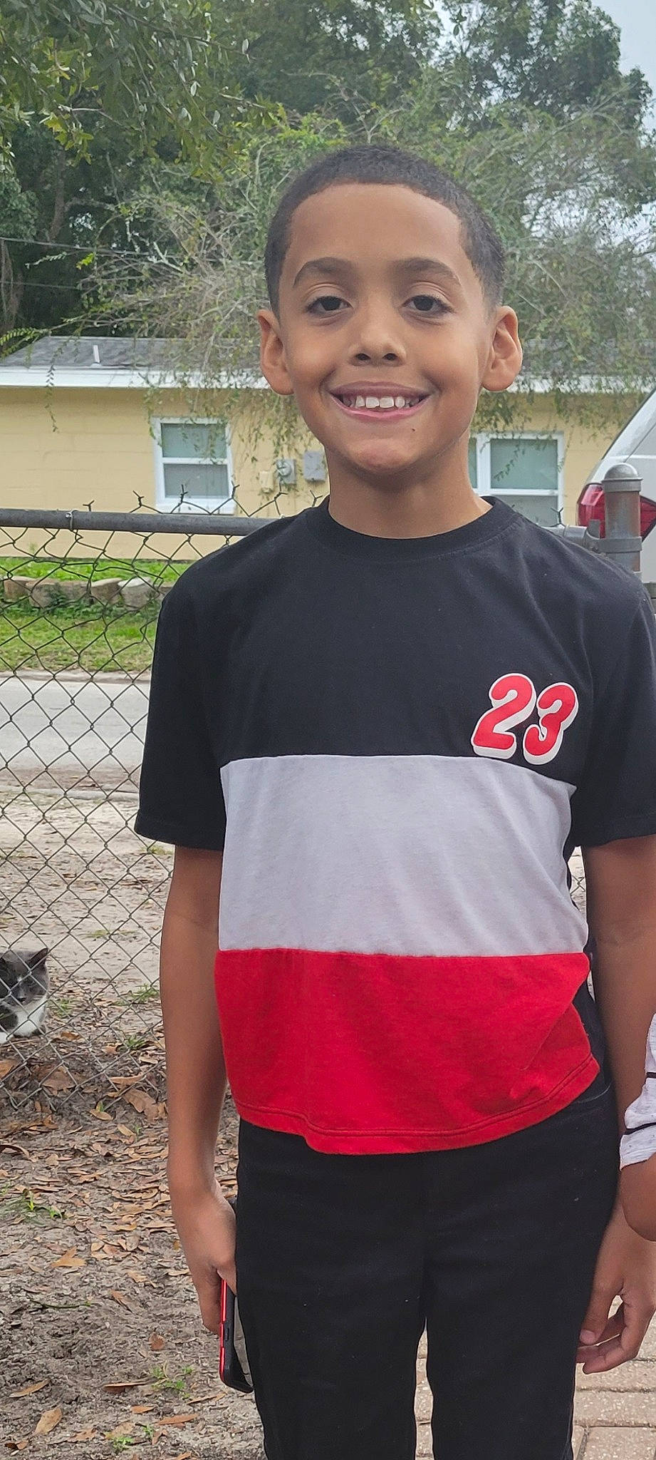 Brett is registered to the contest to win money with this photo: active_shirt, child, electric_blue, fence, fun, grass, happy, joy, leisure, neck, person, plant, recreation, sleeve, smile, soil, t_shirt, team, top, tree