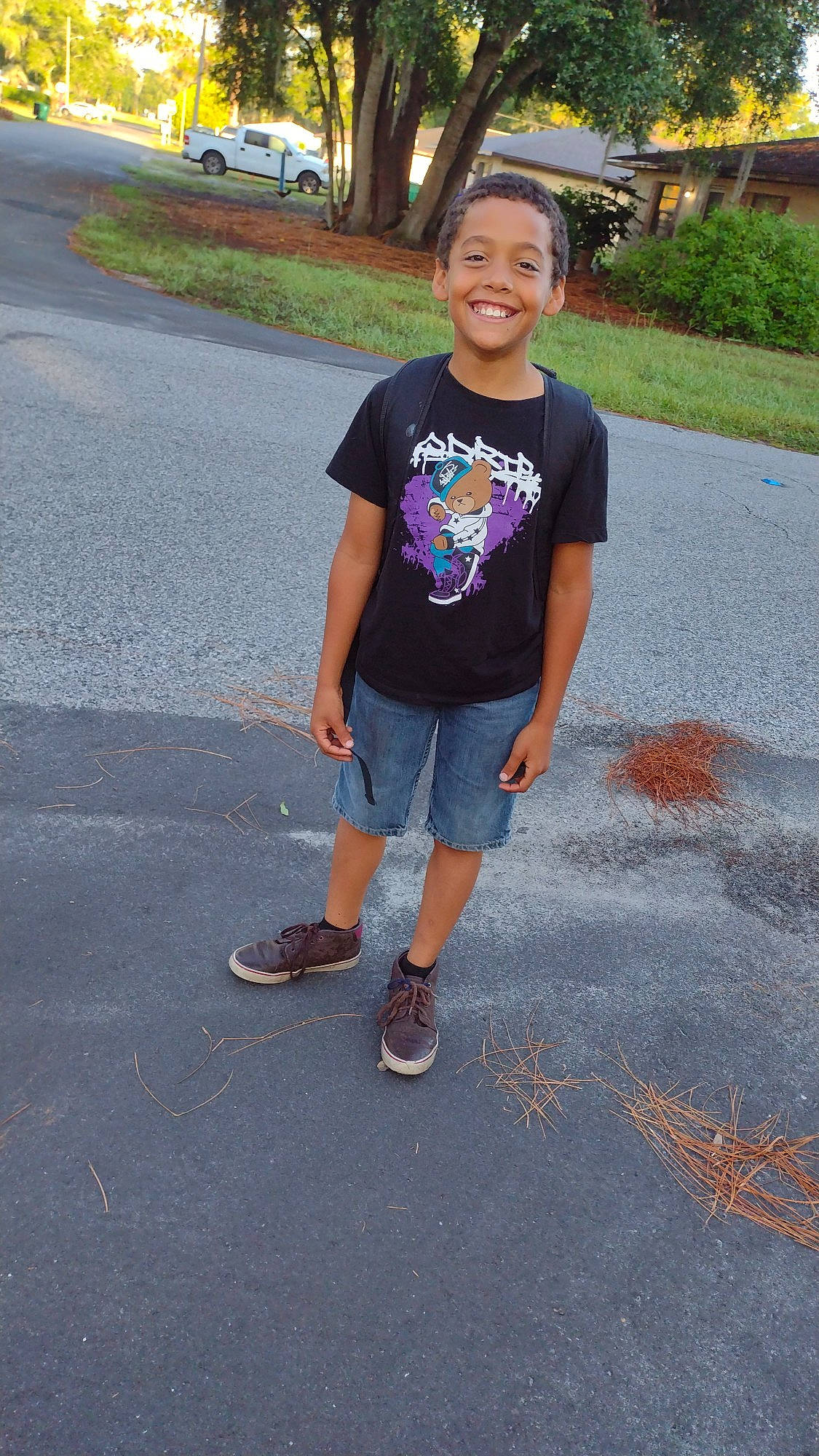 Brett is registered to the contest to win money with this photo: asphalt, child, denim, electric_blue, family_car, fun, grass, happy, joy, leisure, pedestrian, person, plant, recreation, road, road_surface, sandal, shorts, sidewalk, smile