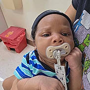 Zalen joined the competition — help win amazing prizes! adult_arm, baby, child, clinic, closeup, cute, expressionless, face, floor, hand, headband, holding, indoor, infant, pacifier, person, striped_clothing, toddler, trash_bin, wall