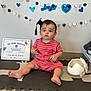 Randall joined the competition — help win amazing prizes! toddler, child, baby, graduation, celebration, headband, cap, certificate, mat, toy, floor, wall_decor, indoor, person, clothing, sitting, expression, cute, achievement, event