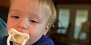 Ryland joined the competition — help win amazing prizes! toddler, child, pacifier, blue_shirt, indoor, hand, face, young_child, blond_hair, portrait, baby, person, closeup, reaching, cute, infant, young, smiling, casual, home