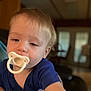 toddler, child, pacifier, blue_shirt, indoor, hand, face, young_child, blond_hair, portrait, baby, person, closeup, reaching, cute, infant, young, smiling, casual, home
