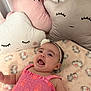 baby, infant, smiling, pink_dress, headband, plush_pillow, cloud_pillow, moon_pillow, star_pillow, blanket, elephant_print, cute, child, happy, indoors, soft_toys, nursery, toddler, bedroom, sleepy_face