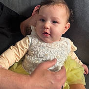 Hope a rejoint le concours — aidez-le/la à gagner de superbes lots ! adult_hand, baby, child, clothing, couch, cozy, cute, fabric, face, family, holding, home_interior, indoor, person, portrait, sitting, skin, soft_lighting, white_tights, yellow_dress