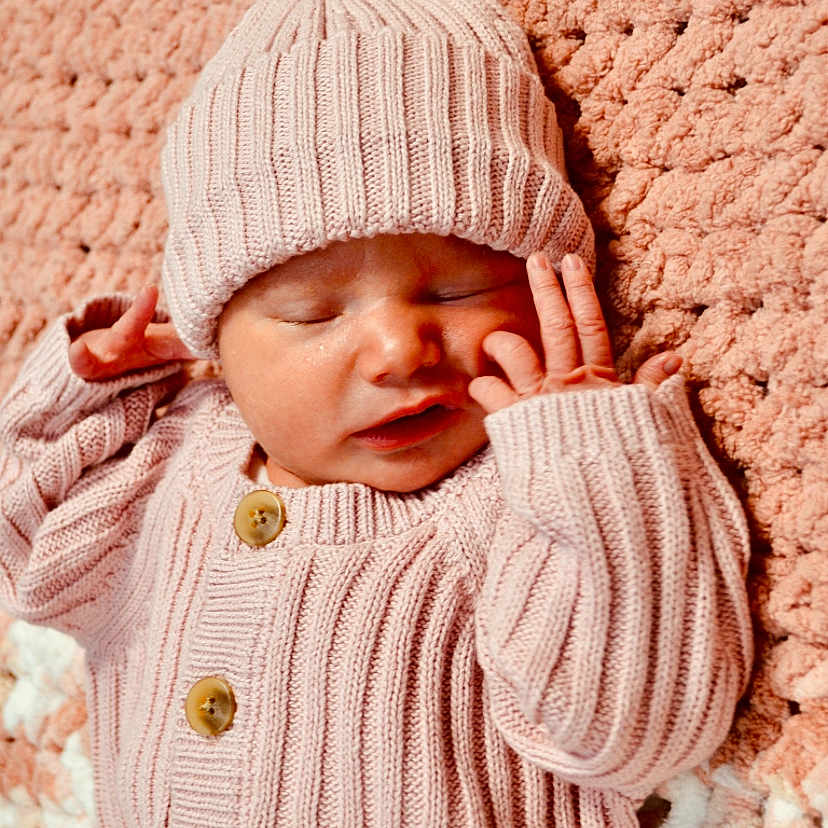 Lesleigh joined the competition — help win amazing prizes! baby, blanket, bonnet, cap, clothing, face, hat, head, knitwear, newborn, person, photography, portrait, sad, sleeping, sweater, yawning