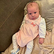 Ivy-Leigh is registered to the contest to win money with this photo: baby, infant, dress, pink, blue_shoes, blanket, sofa, couch, cute, child, person, footwear, indoor, home, clothing, expression, sitting, cozy, soft, portrait