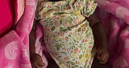 Tylynn is registered to the contest to win money with this photo: baby, child, infant, smiling, happy, blanket, pink, onesie, socks, lying_down, cozy, soft, floral_pattern, cute, joyful, indoors, person, toddler, portrait, sleepwear