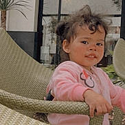 Kamila is registered to the contest to win money with this photo: building, candid, chair, child, curly_hair, daylight, face, furniture, outdoor, patio, person, photography, pink_clothing, plant, portrait, sitting, smiling, toddler, window, woven_chair