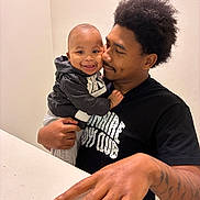 Katrell Jr is registered to the contest to win money with this photo: baby, child, man, father, smile, hug, affection, indoor, black_hair, hoodie, tattoo, hand, portrait, people, happy, love, casual_clothing, person, baby_clothes, skin