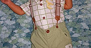 Azael joined the competition — help win amazing prizes! baby, infant, child, suspenders, green_shorts, plush_blanket, patterned_shirt, lying_down, cute, soft_texture, footwear, indoors, portrait, small_hands, curious_expression, clothing, head, face, skin, young