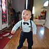 Kohen is registered to the contest to win money with this photo: baby, blurred_background, bow_tie, boy, carpet, child, clothing, cute, doorway, fashion, happy, hardwood_floor, home, indoors, person, portrait, smiling, suspenders, toddler, walking