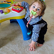Calixte a rejoint le concours — aidez-le/la à gagner de superbes lots ! toddler, child, pacifier, toy, floor, blue_eyes, hair_tie, indoor, plaid_shirt, overalls, curious, crawling, baby_toy, colorful, hand, foot, carpet, person, playing, cute