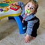 toddler, child, pacifier, toy, floor, blue_eyes, hair_tie, indoor, plaid_shirt, overalls, curious, crawling, baby_toy, colorful, hand, foot, carpet, person, playing, cute